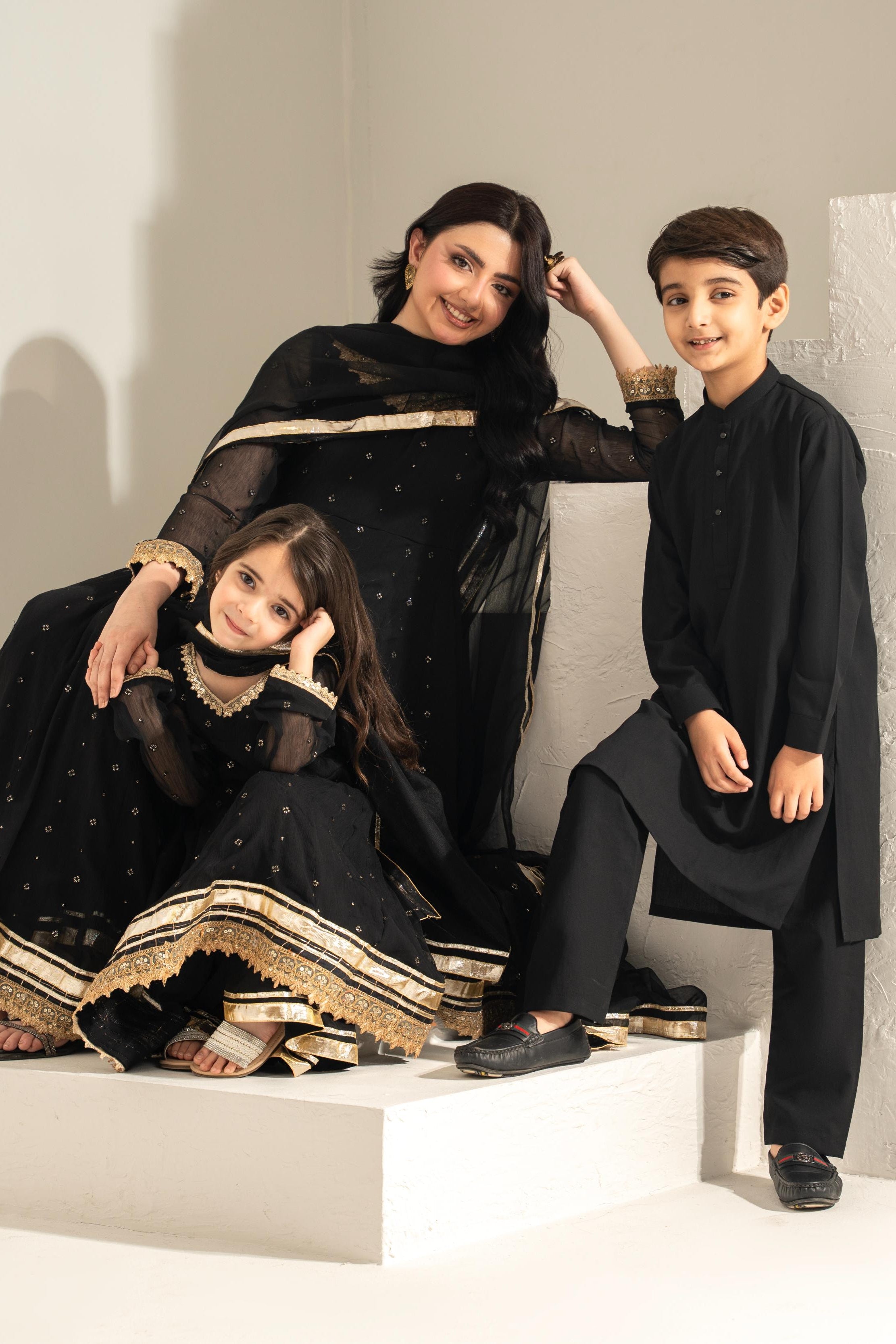 Woman and two children in formal attire sitting on a staircase.